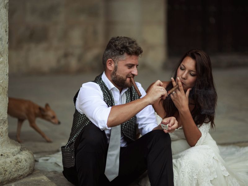 Bride and groom enjoying cigars at their wedding reception